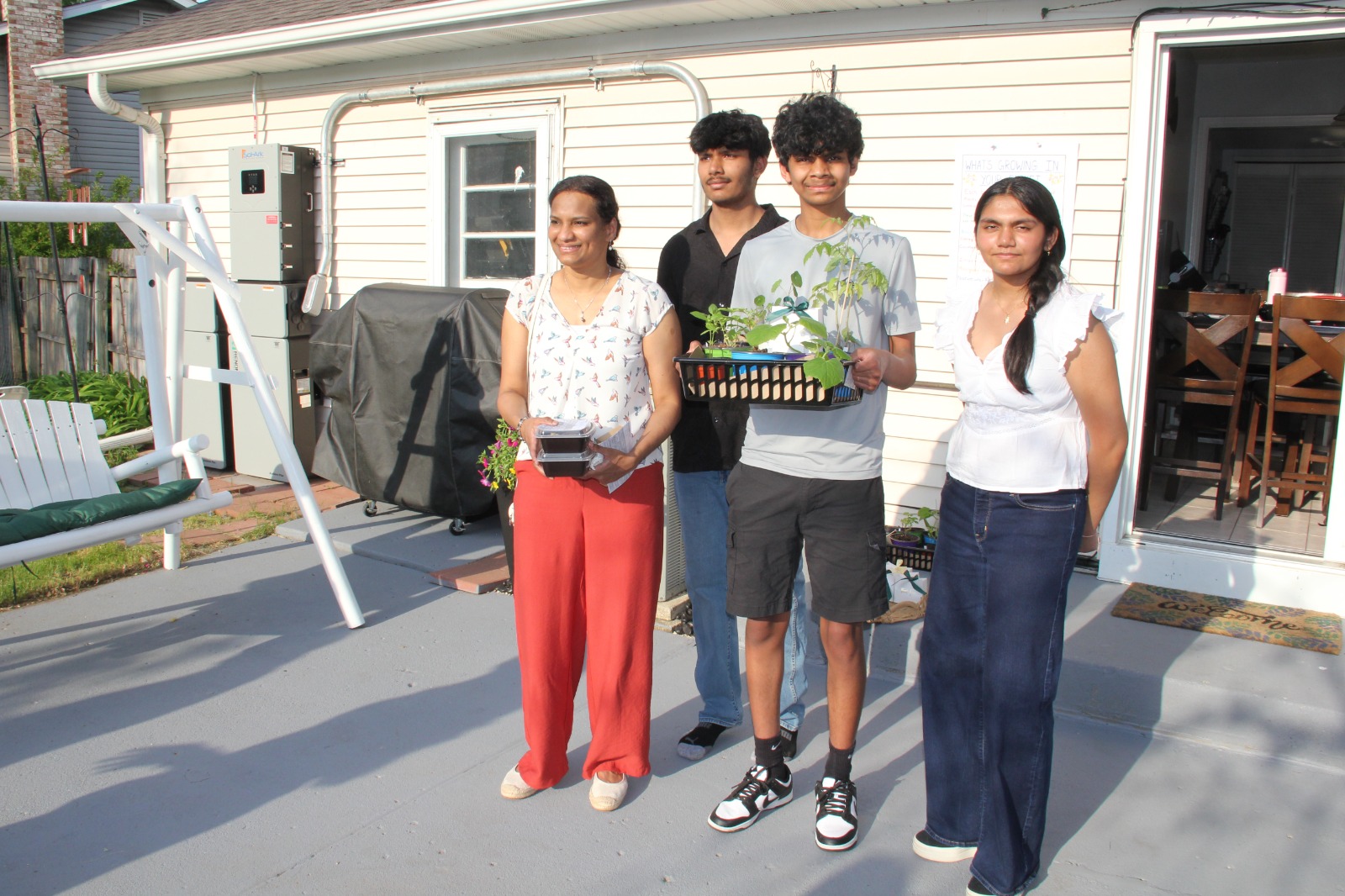 Mom and three teens posed on the patio with their plant giveaway basket and takeaway containers