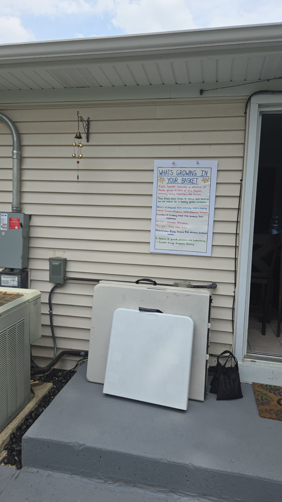 What's Growing in Your Basket board hung on the patio wall with folded tables ready for setup