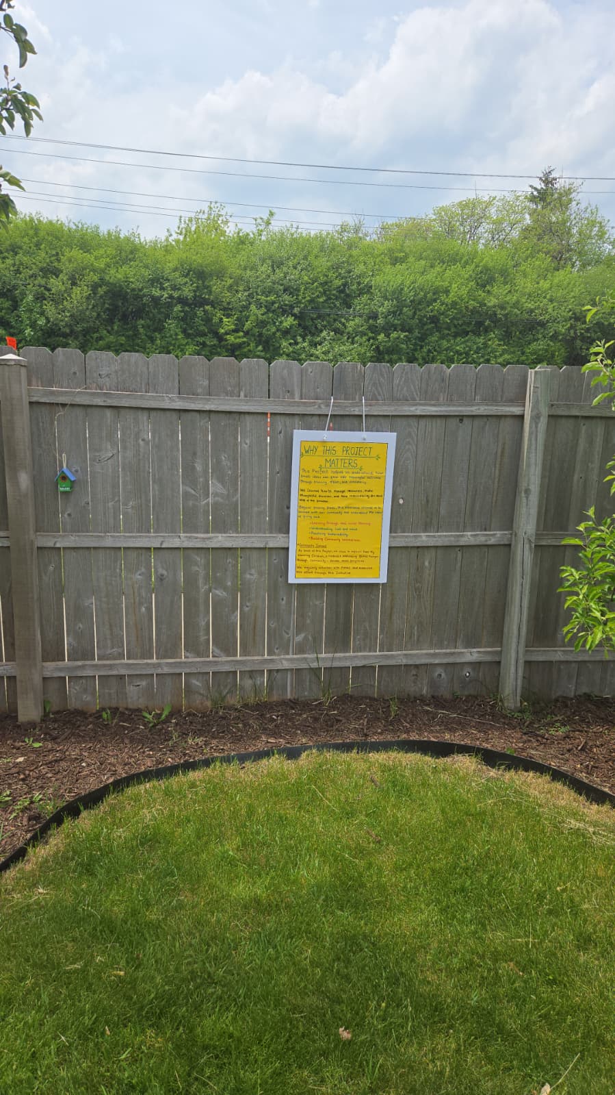 Why This Project Matters board mounted on the backyard fence during setup