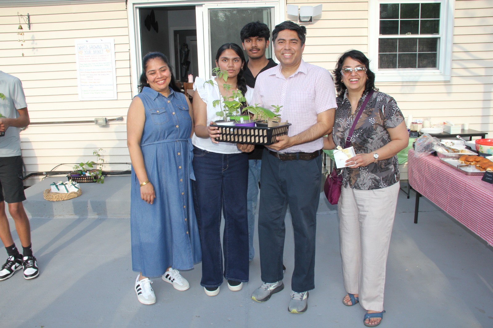 Guest family of five posed on the patio holding their Seeds of Hope giveaway basket beside the menu board