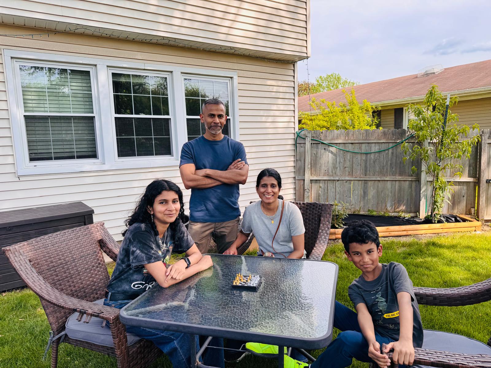 Family of four playing chess together at the patio table during the event