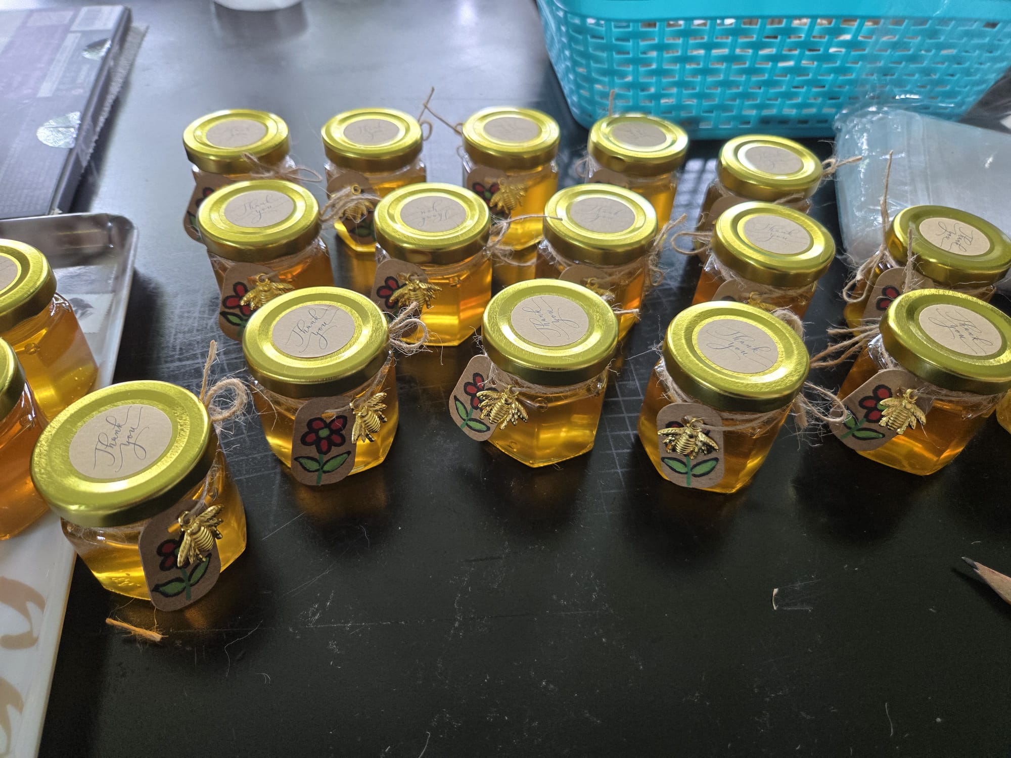 Full batch of mini honey jar favors with Thank You labels and bee charms arranged for the event