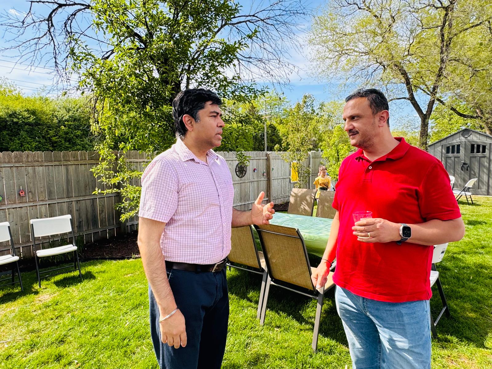Two guests in conversation in the backyard with seating and shed in background