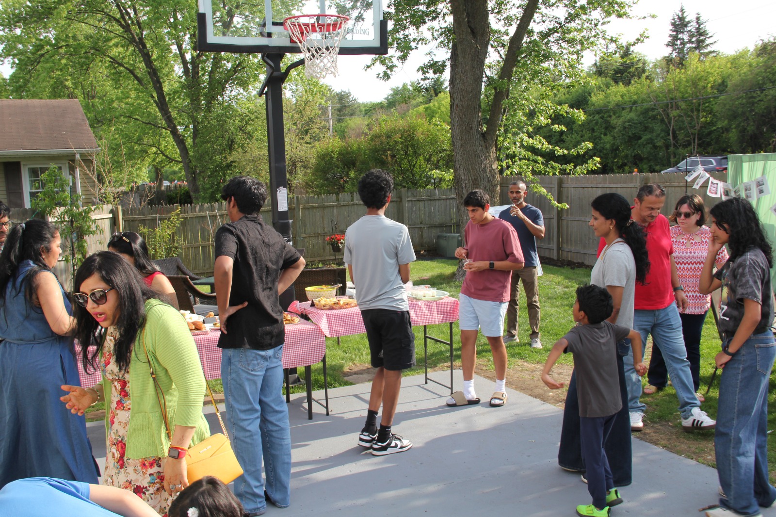 Teen friends and families mingling on the basketball court near the dessert table